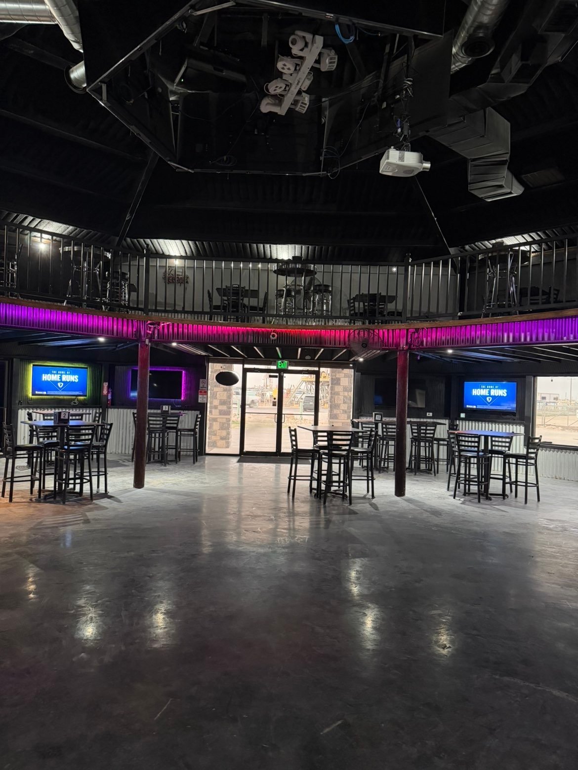 Empty modern nightclub interior with neon pink lighting, bar seating, and industrial ceiling